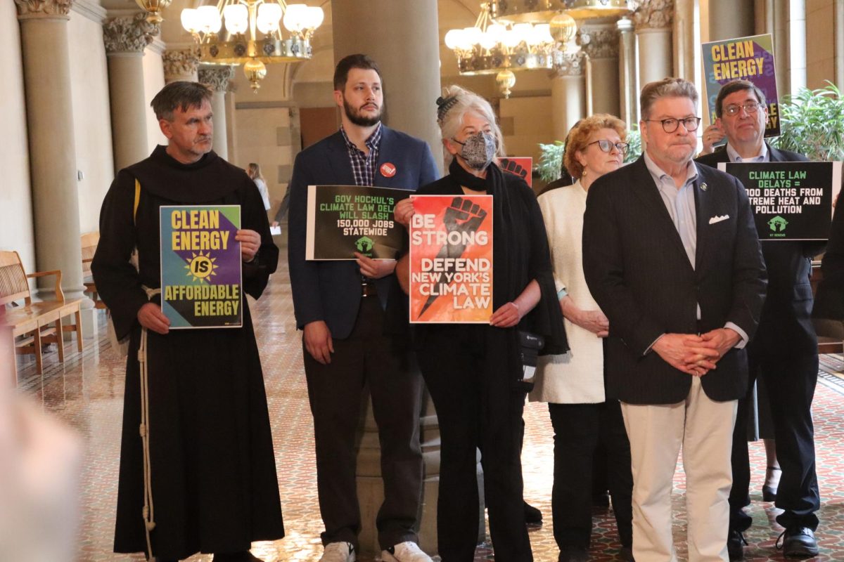 Lawmakers and advocates gather in the capitol holding signs. 